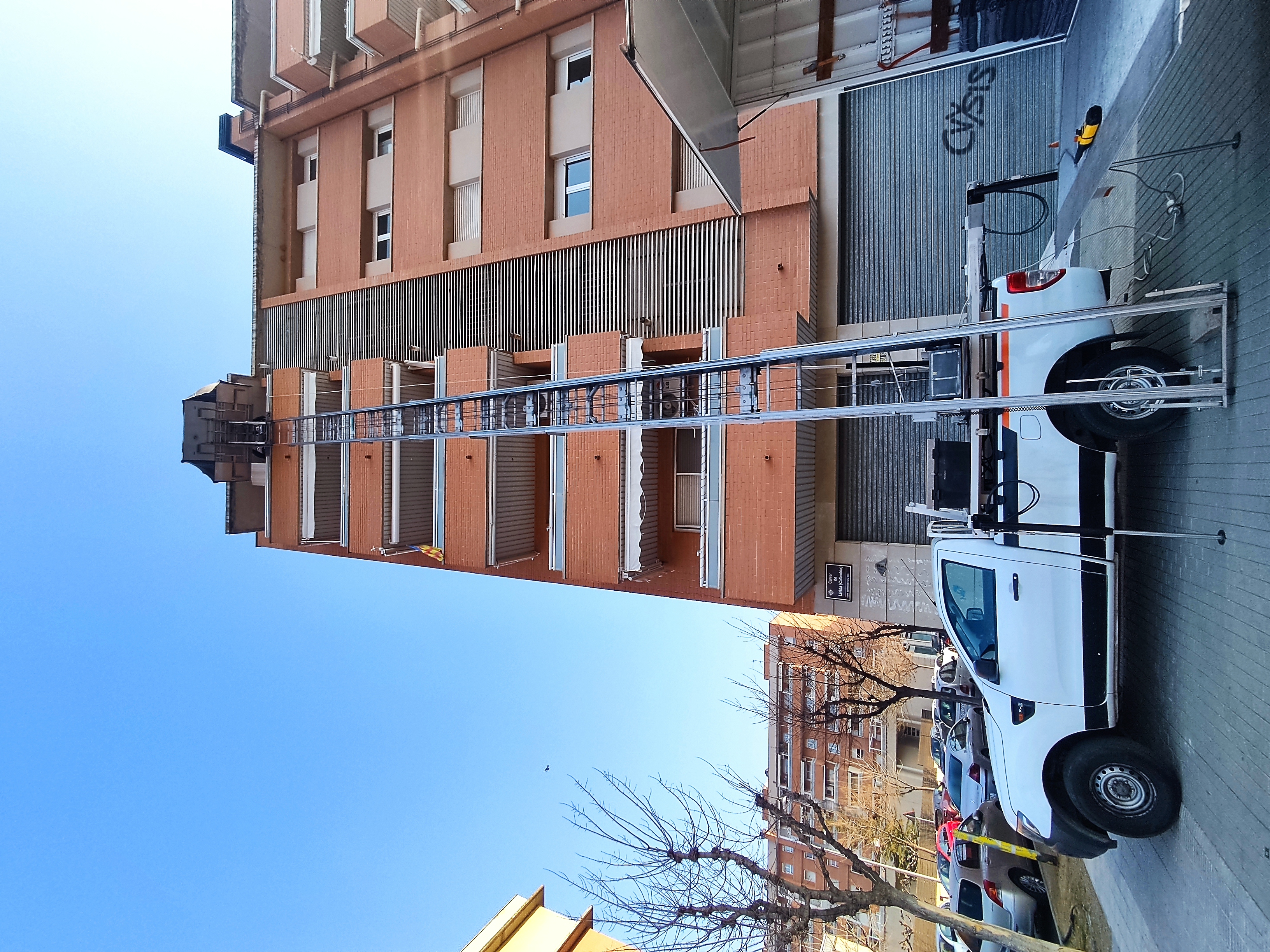 Camió grua de Mudances Sabaté davant edifici de totxo vermell