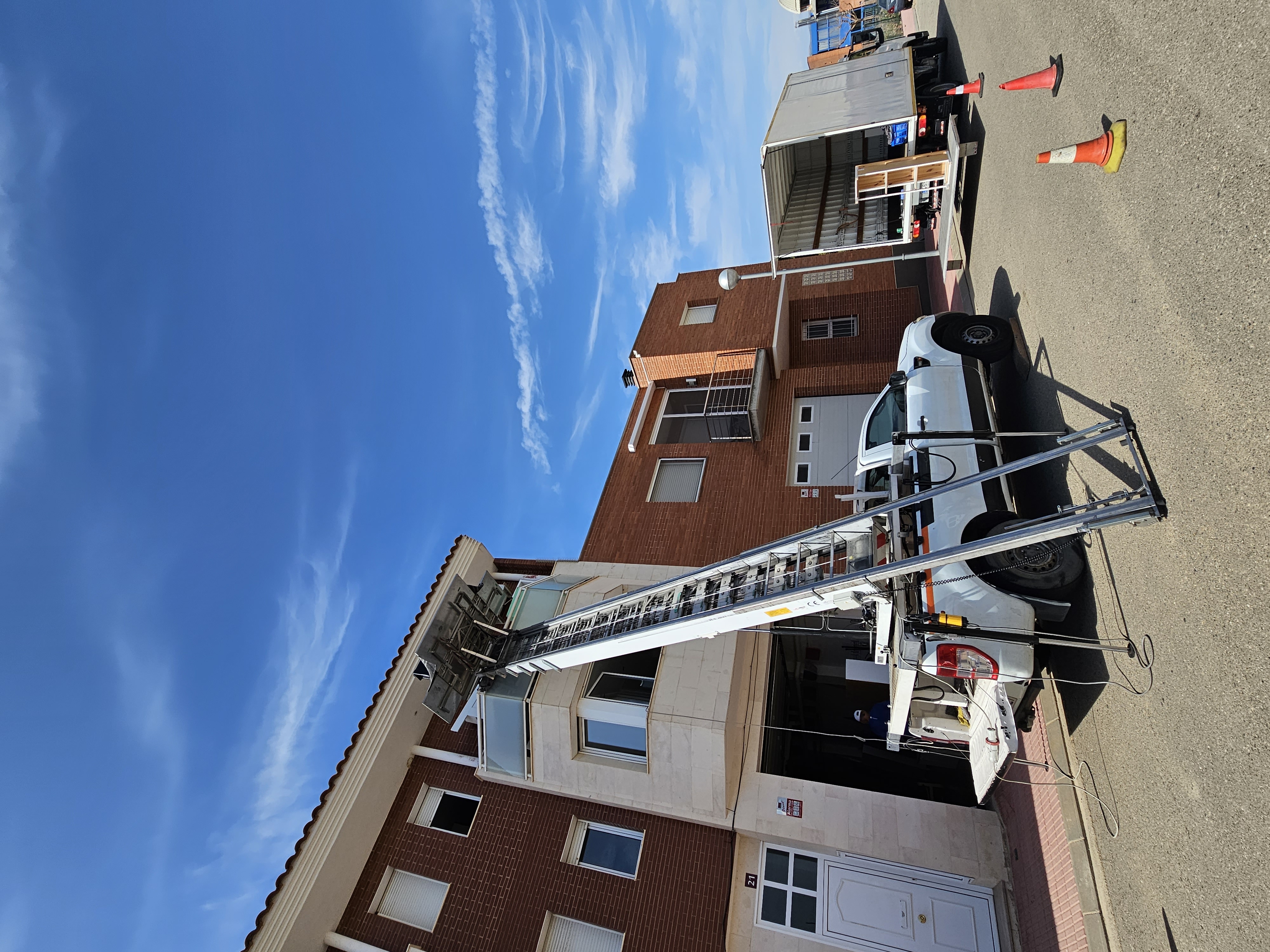 Camió grua de Mudances Sabaté davant bloc de pisos de totxo