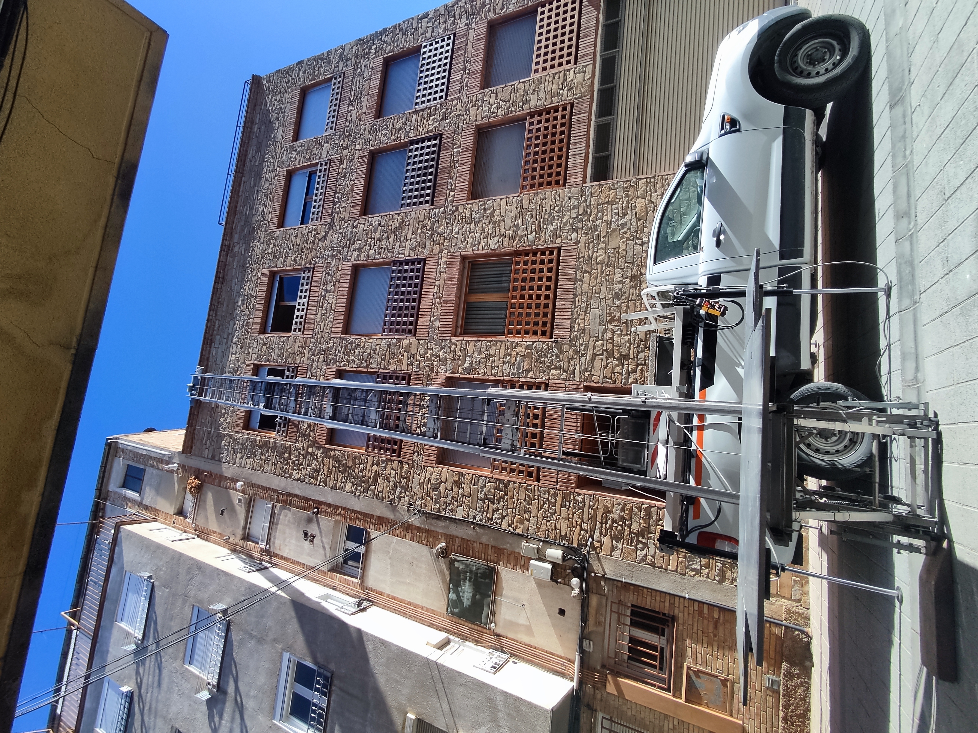 Camió grua de Mudances Sabaté davant edifici de pedra amb façana rústica